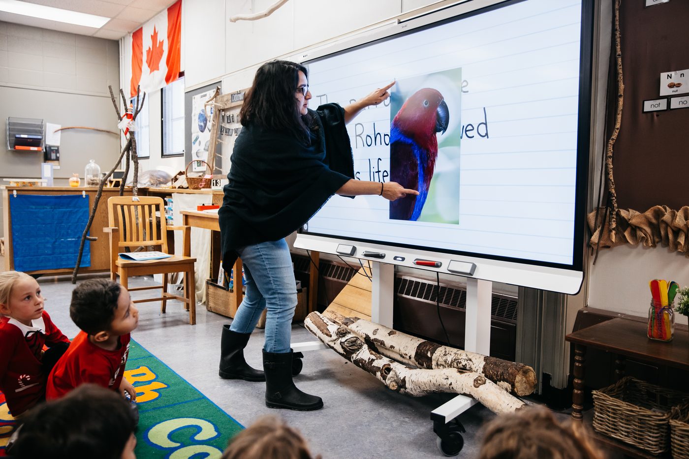 A teacher and young students at a Technetix SMART display in a classroom